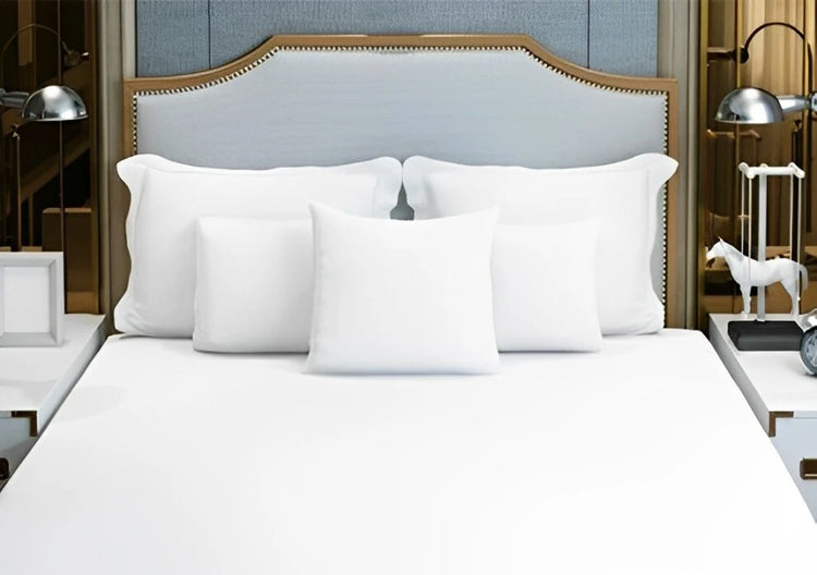 Close-up of various pillow inserts neatly arranged on a white bed.