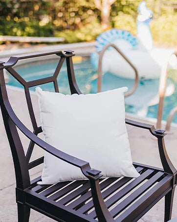 White pillow on outdoor chair, enhancing comfort and relaxation.